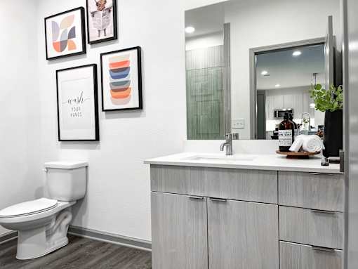 A bathroom with a toilet, sink, and framed pictures on the wall.